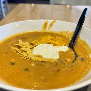 a bowl of soup with tortilla and sour cream