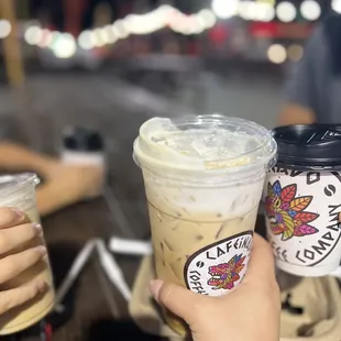 a hand holding two cups of coffee