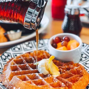 a person pouring syrup on a waffle