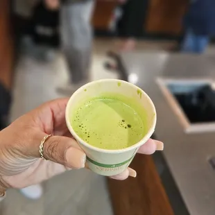 a person holding a cup of green tea