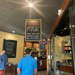 a man in a blue shirt standing in front of a coffee shop