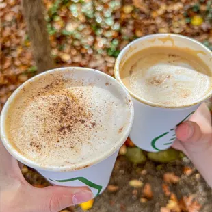 two people holding cups of coffee