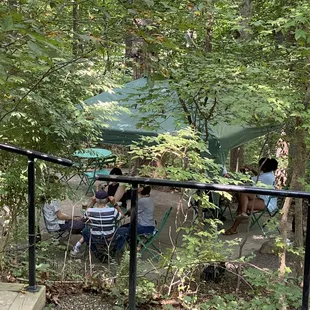 a group of people sitting at a table in the woods