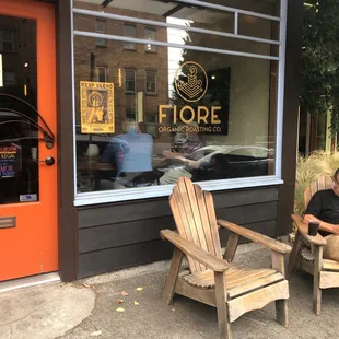 a man sitting in a chair in front of a coffee shop