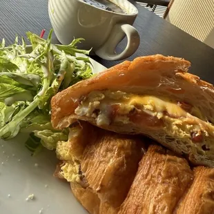 Breakfast croissant with greens and a coffee.