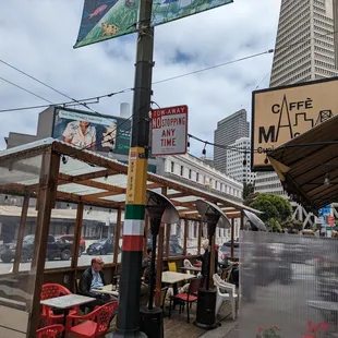 people sitting at tables on the sidewalk