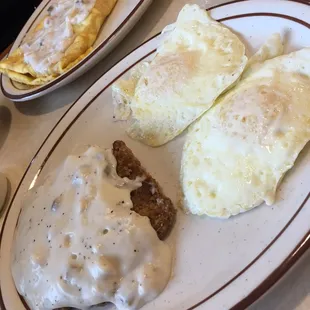 Country fried steak and eggs. Across the table ham and cheese omelet with gravy.