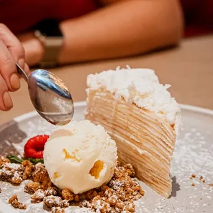 a person scooping ice cream into a piece of cake