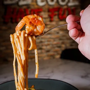 a hand holding a fork full of pasta