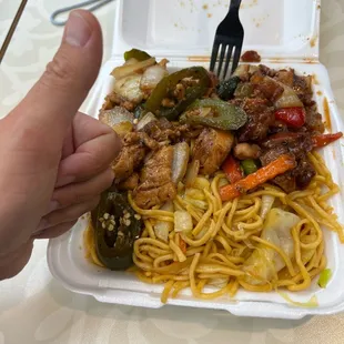a hand holding a fork over a plate of food