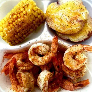 a plate of shrimp, corn and potatoes