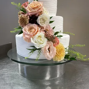 a three tiered wedding cake with fresh flowers
