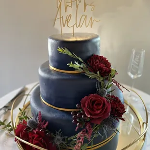 a three tiered cake with red flowers