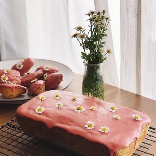 a cake with pink icing and white flowers