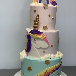 a three tiered cake with a rainbow and stars on top