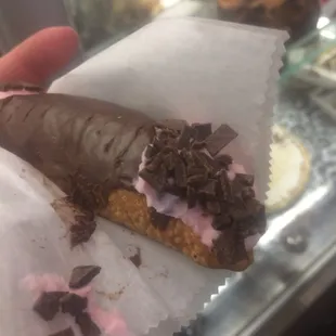 a hand holding a chocolate covered pastry