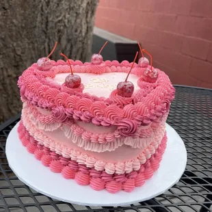 a pink cake with cherries on top