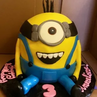 a minion sitting on a birthday cake