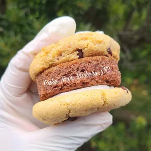 a hand holding a chocolate chip cookie sandwich