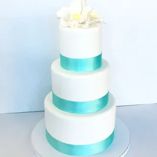 3-tiered wedding cake bordered with blue ribbon.