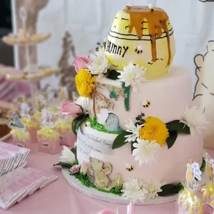 a pink cake with a honey pot on top