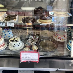 a variety of cakes in a display case