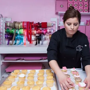 a woman decorating cupcakes