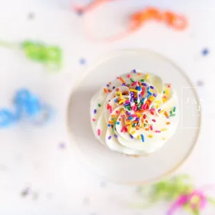 a cupcake with white frosting and sprinkles