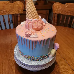 a pink and blue cake with ice cream and sprinkles