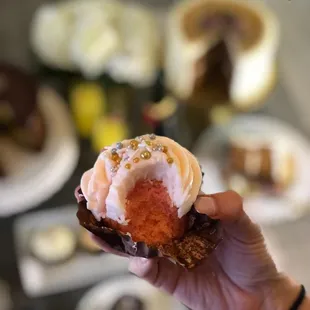 a hand holding a strawberry cupcake