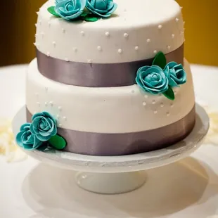 My adorable wedding cake by Ginene.  Fondant frosting, silver ribbon, blue sugar flowers.