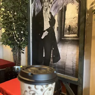 a cup of coffee in front of a picture of an angel