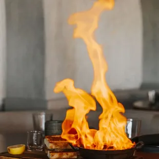 Flaming Saganaki: Fried Kasseri cheese, kalamata olive, house made foccaia, Greek brandy, &amp; Lemon