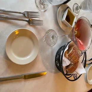 a table set with wine glasses, plates and utensils