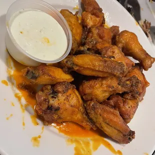 a plate of chicken wings with a side of ranch sauce