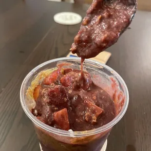 a person dipping a piece of meat into a bowl of food