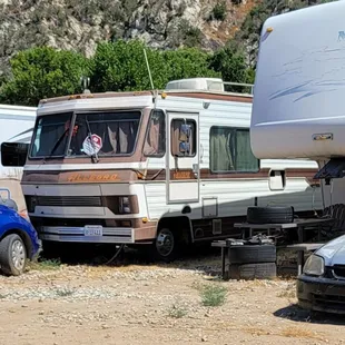 Trash around and under crammed together rigs with broken down vehicles etx