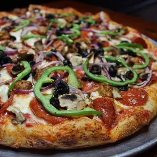 a pizza with pepperoni, mushrooms, olives, and peppers