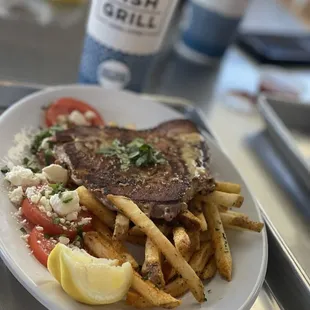 Seared Aji tuna on a bed of french fries with a side of tomatos and feta.