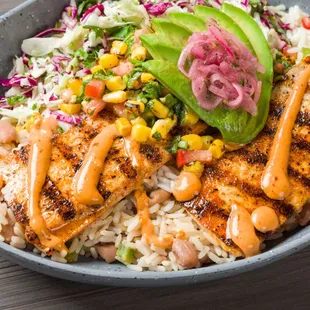 Mahi Mahi Bowl Cali-Style, grilled Mahi, white rice, beans, diced chili mix, with avocado corn salsa, chipotle aioli &amp; pickled onions.