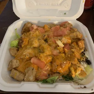 a takeout container with chicken and cheese