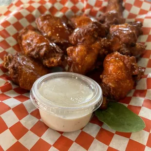 a basket of fried chicken with a side of ranch sauce