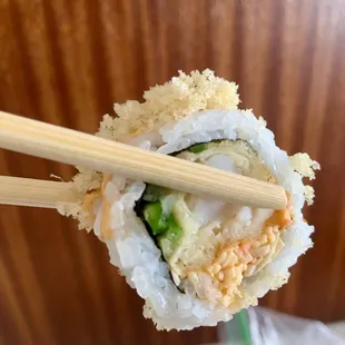  close up of a sushi roll with chopsticks