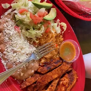 a plate of chicken, rice, and salad