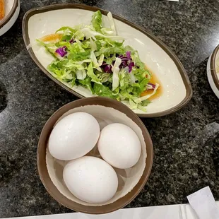 a plate of eggs and a bowl of salad