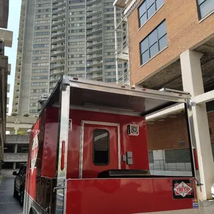a red food truck parked in front of a tall building