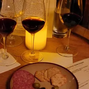 a plate of cheese, olives, and two glasses of wine