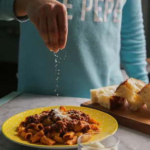 a person sprinkling salt onto a plate of pasta
