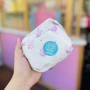 a hand holding a bag of donuts
