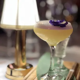 a drink in a glass with a purple flower